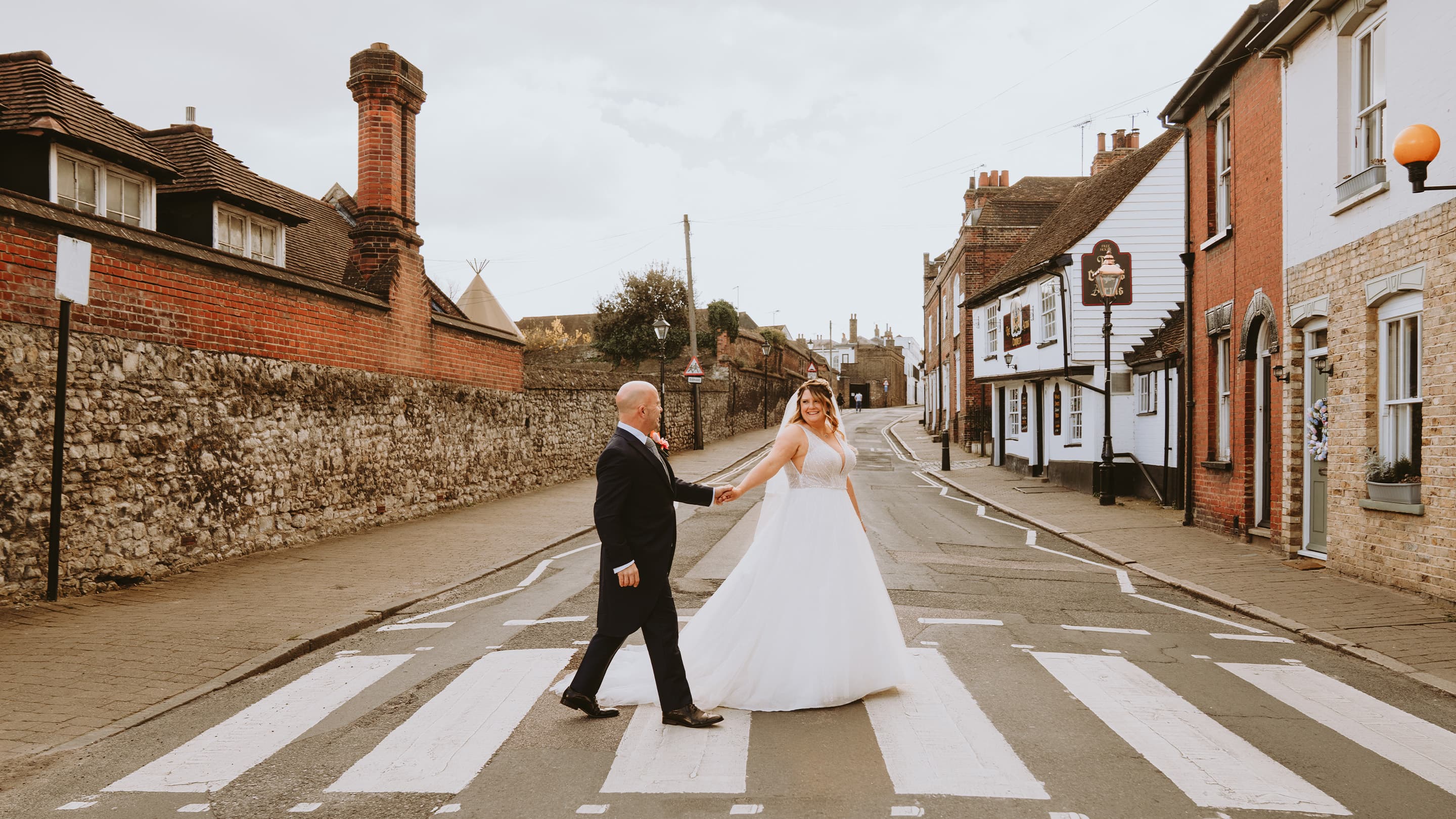 Bride and groom holding hands crossing a street in Rochester, UK