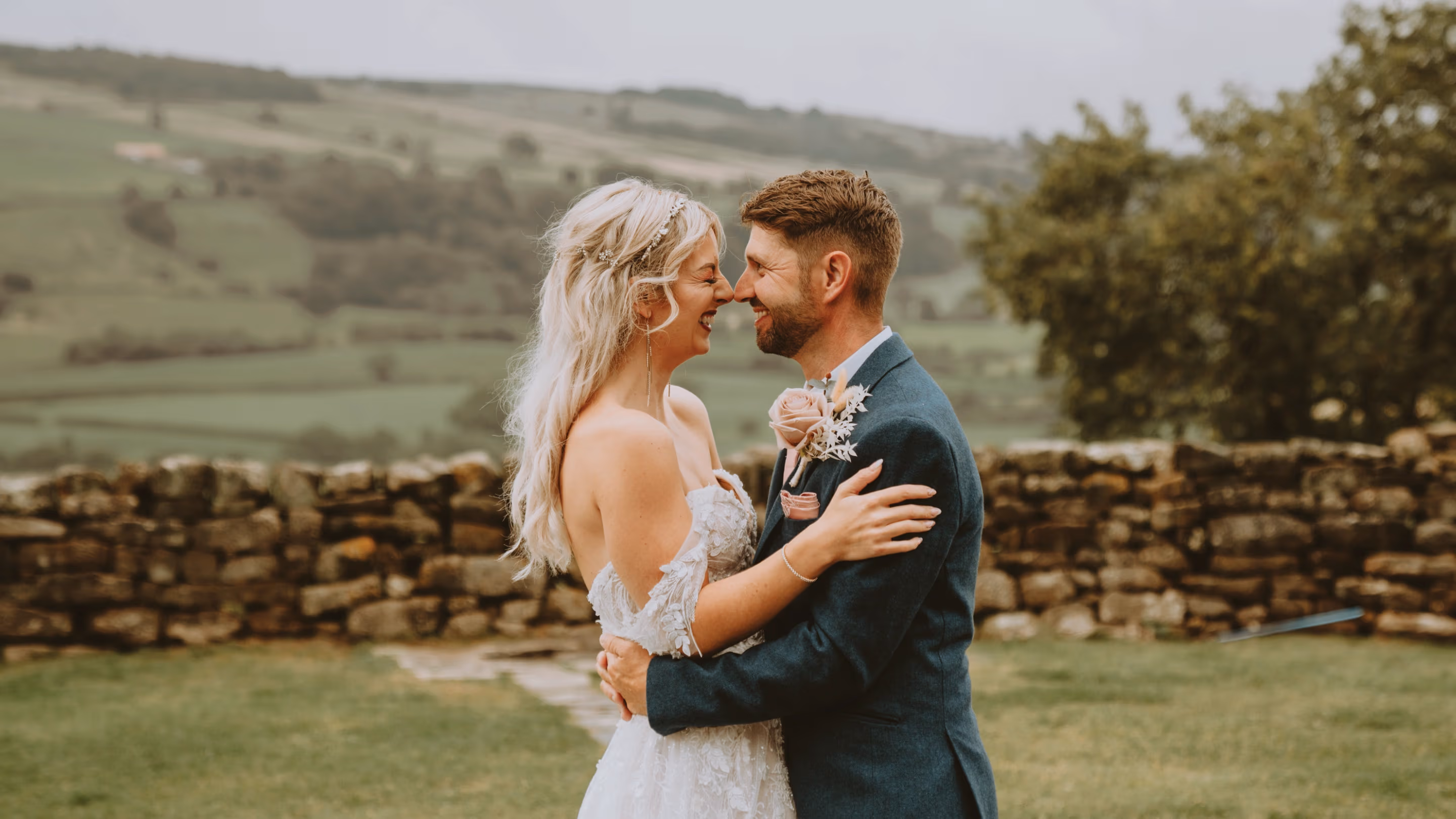 Bride and groom embracing during an outdoor UK wedding with countryside backdrop
